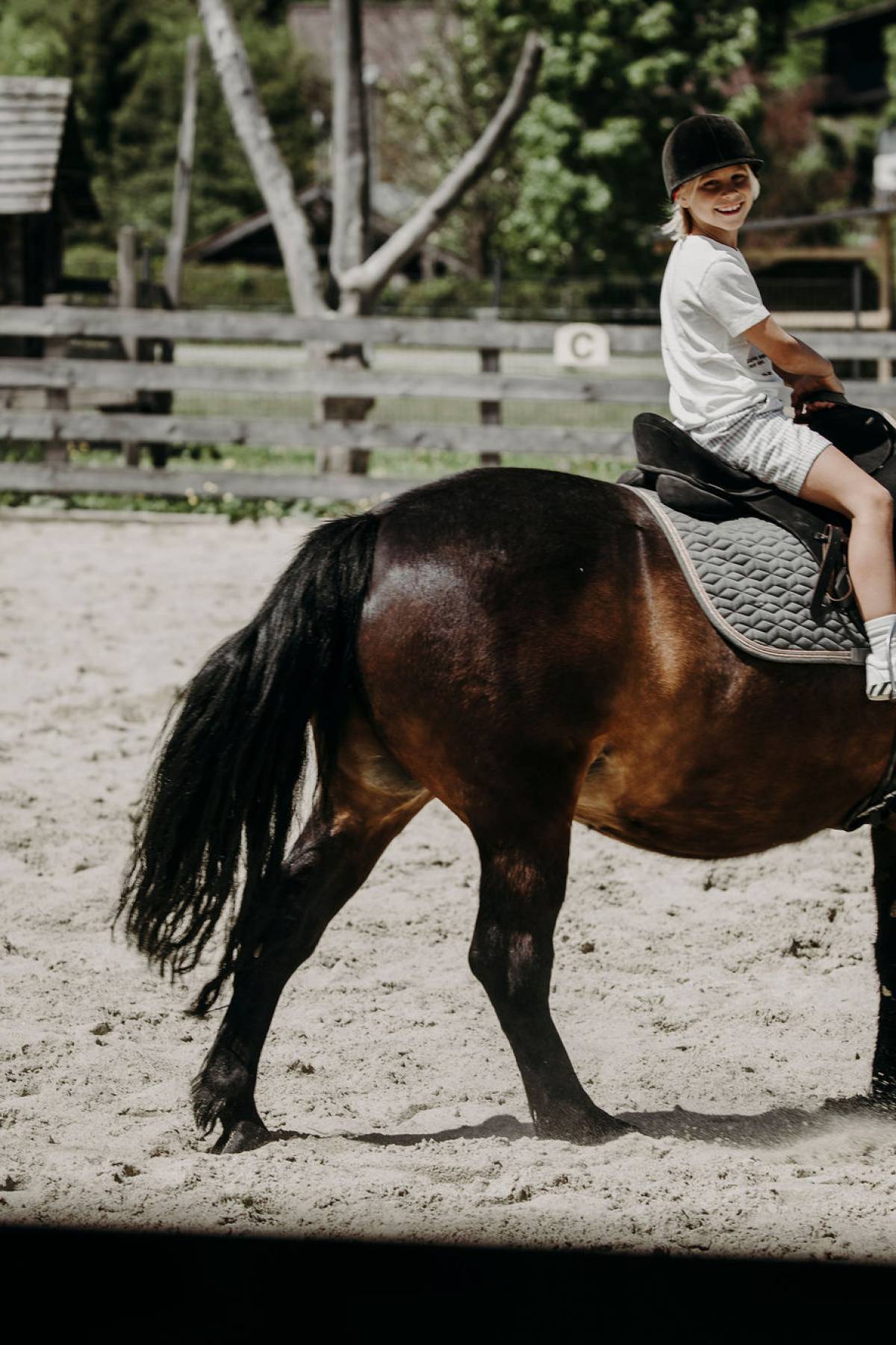 Kind reitet auf braunem Pferd im Ferienresort Central Flachau