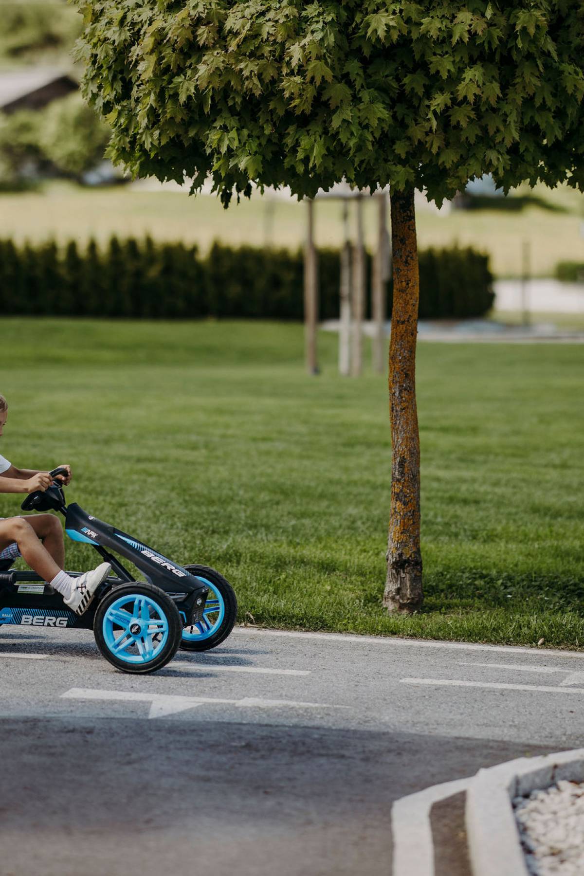 Blondes Kind fährt mit blau-schwarzem Go Kart den Berg hinunter