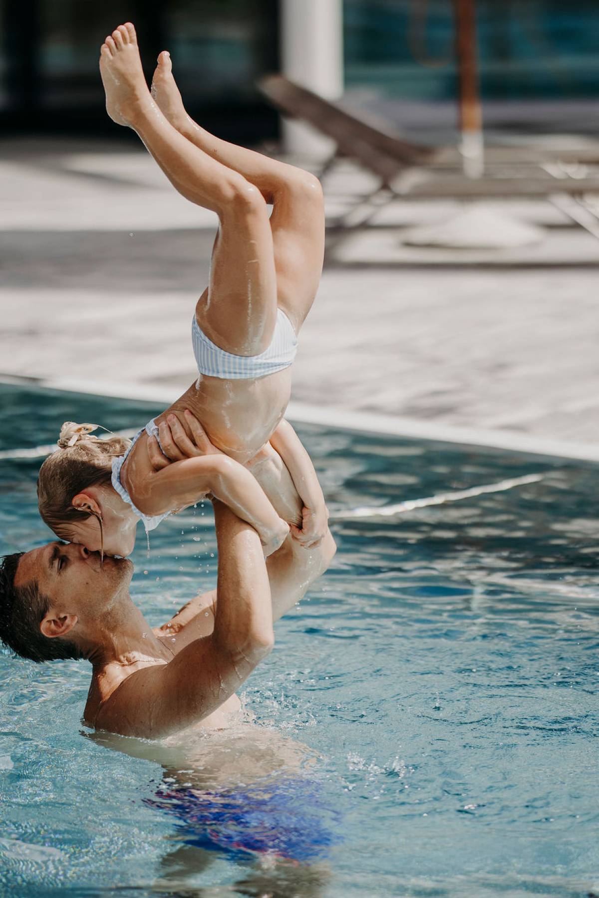 Vater stemmt Tochter im Pool in die Höhe