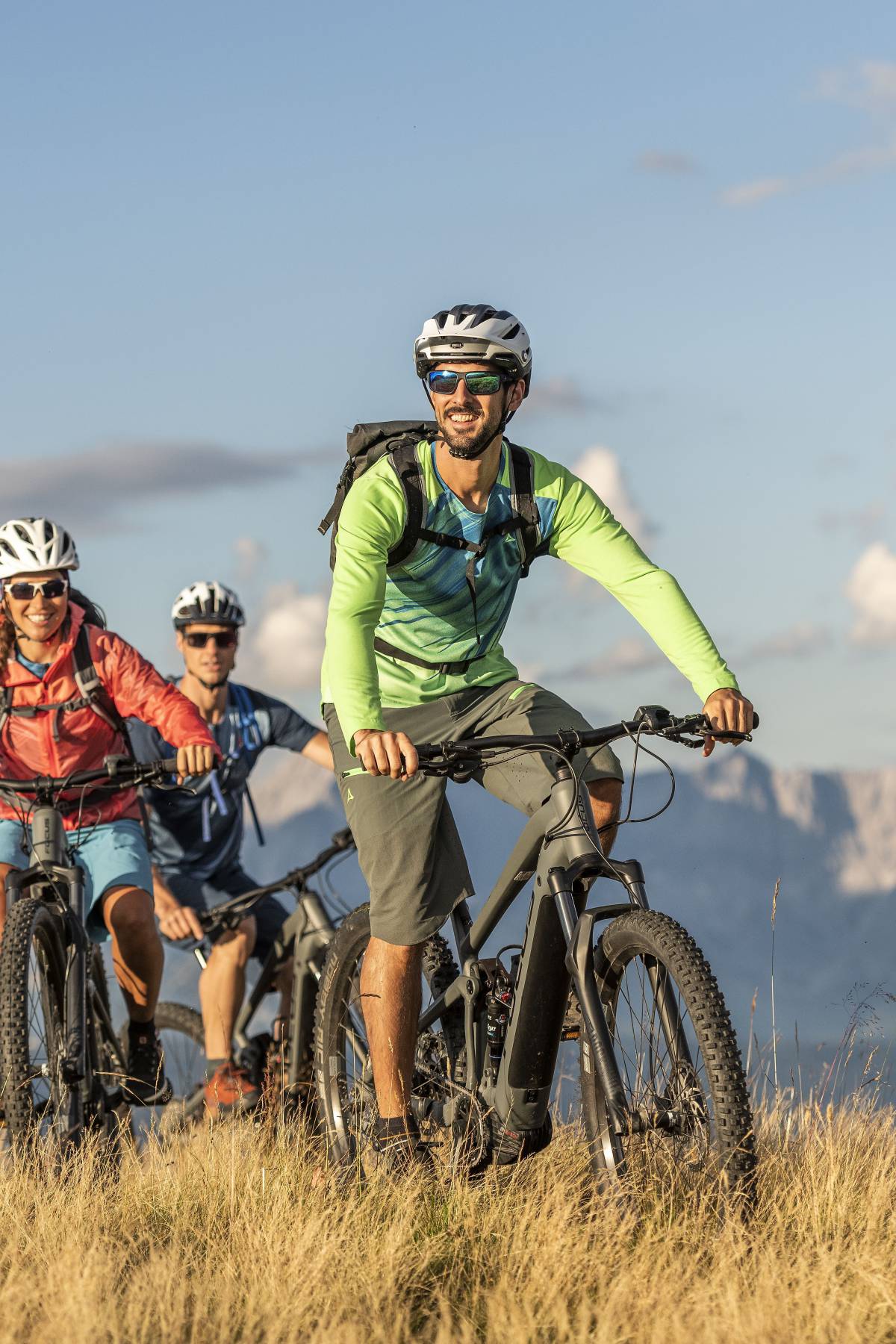 Drei Mountainbiker in den Alpen bei Flachau vor Bergpanorama