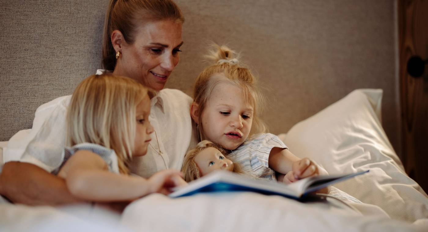 Mutter liest Töchtern im Bett ein Buch vor