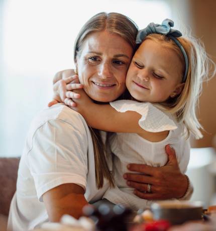 Blondes Mädchen umarmt lächelnde Mutter