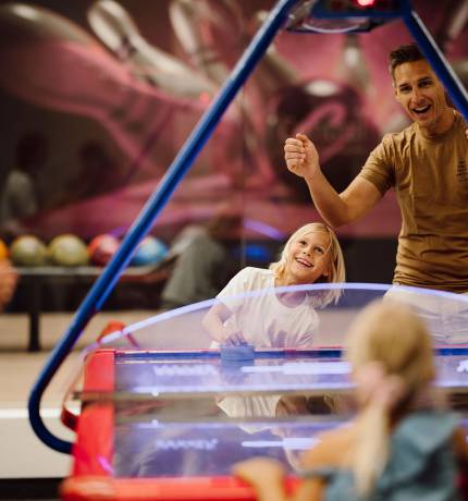 Familie vergnügt sich beim Airhockey im Ferienresort Central Flachau