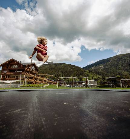 Junge springt auf Trampolin im Outdoor-Bereich des Ferienresort Central Flachau