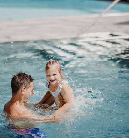 Vater und Tochter plantschen gemeinsam im Pool des Ferienresort Central Flachau