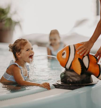 Fisch Nemo spritzt Wasser auf Mädchen im Kleinkindbecken