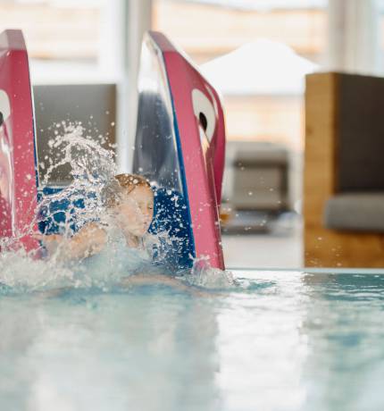 Kind rutscht auf kleiner Rutsche ins Wasser