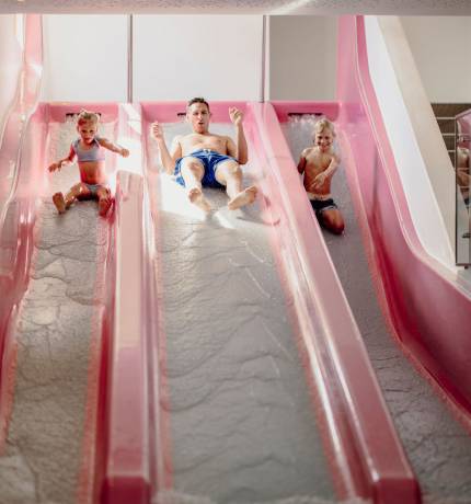 Kinder und Vater auf einer roten Wasserrutsche im Ferienresort Central Flachau