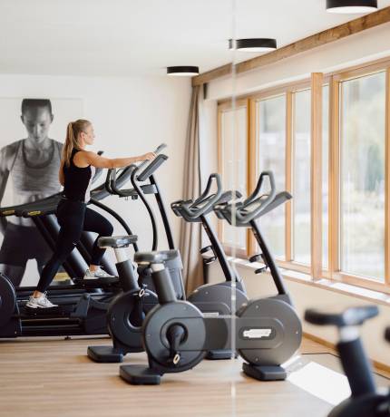 Frau auf Stepper trainiert im Fitnessraum des Ferienresort Central Flachau