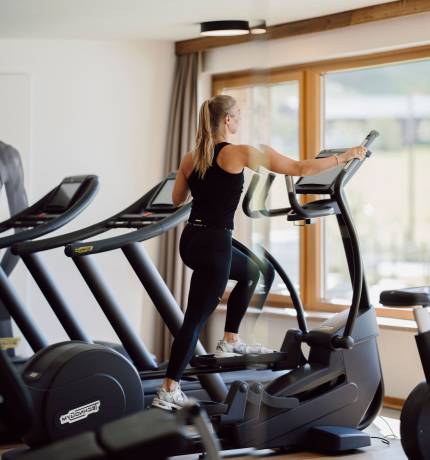 Spiegelbild einer Frau auf dem Stepper im Fitnessraum