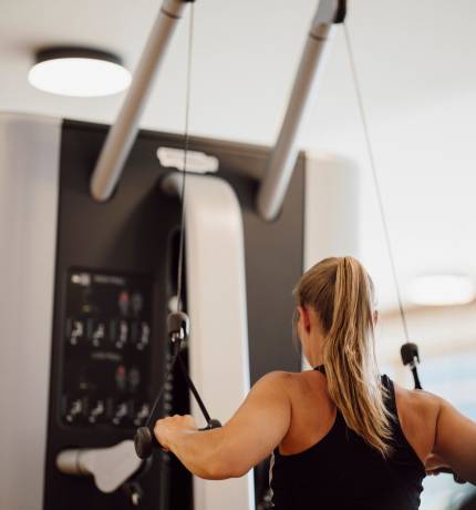 Frau von hinten am Fitnessgerät im Ferienresort Central Flachau