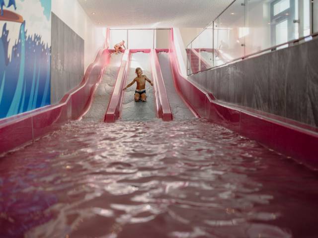 Kinder rutschen auf roter Wasserrutsche im Ferienresort Central Flachau