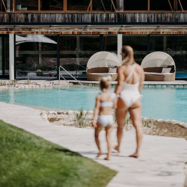 Frau und Kind gehen am Schwimmteich des  Ferienresort Central Flachau entlang